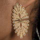 A woman wearing a pair of Cremilde Bispo Jewellery Guipure Topaz GP earrings with blue topaz gemstones.