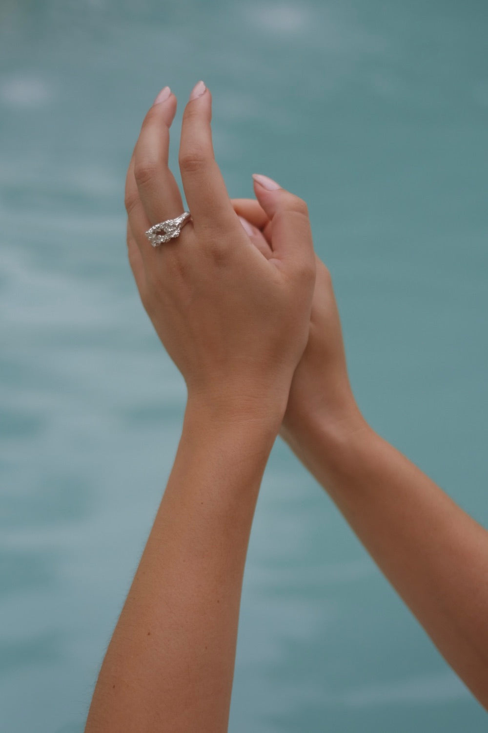 A woman's hand holding the Glade ring from Cremilde Bispo Jewellery in the water.