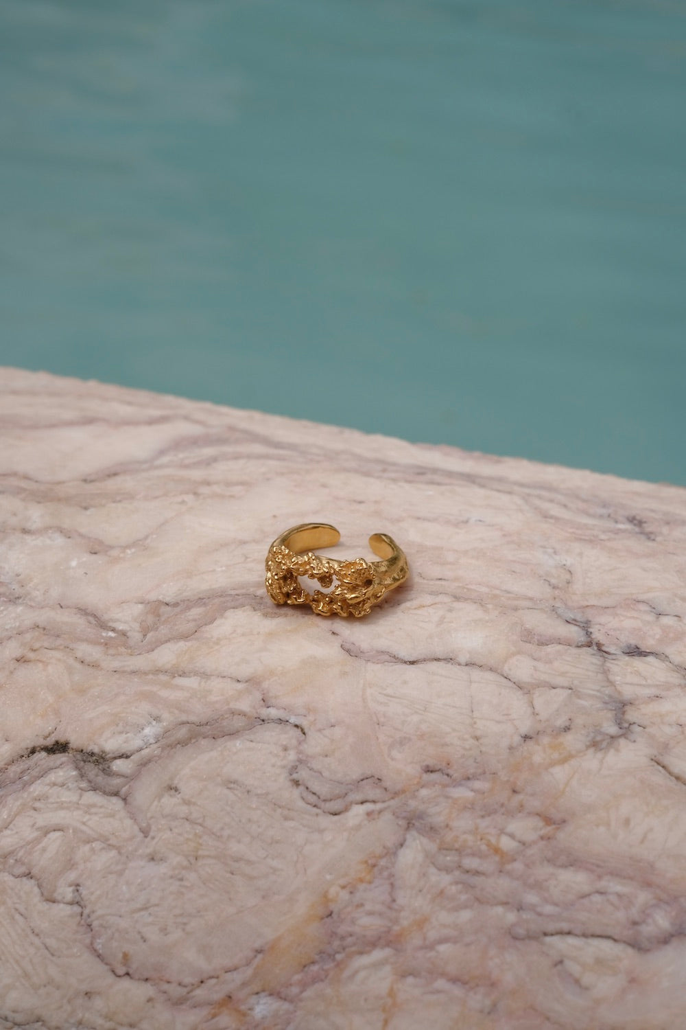 A handcrafted The Glade ring GP from the Cremilde Bispo Jewellery collection sitting on top of a marble pool.