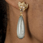 A woman wearing a pair of Cremilde Bispo Jewellery Muse III Toed eye earrings with a green stone.
