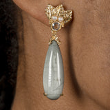 A woman wearing a pair of Cremilde Bispo Jewellery Muse III Toed eye earrings with a green stone.