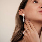 A woman wearing a pair of The Muse III Toed eye earrings with natural drop-shaped gemstones by Cremilde Bispo Jewellery.