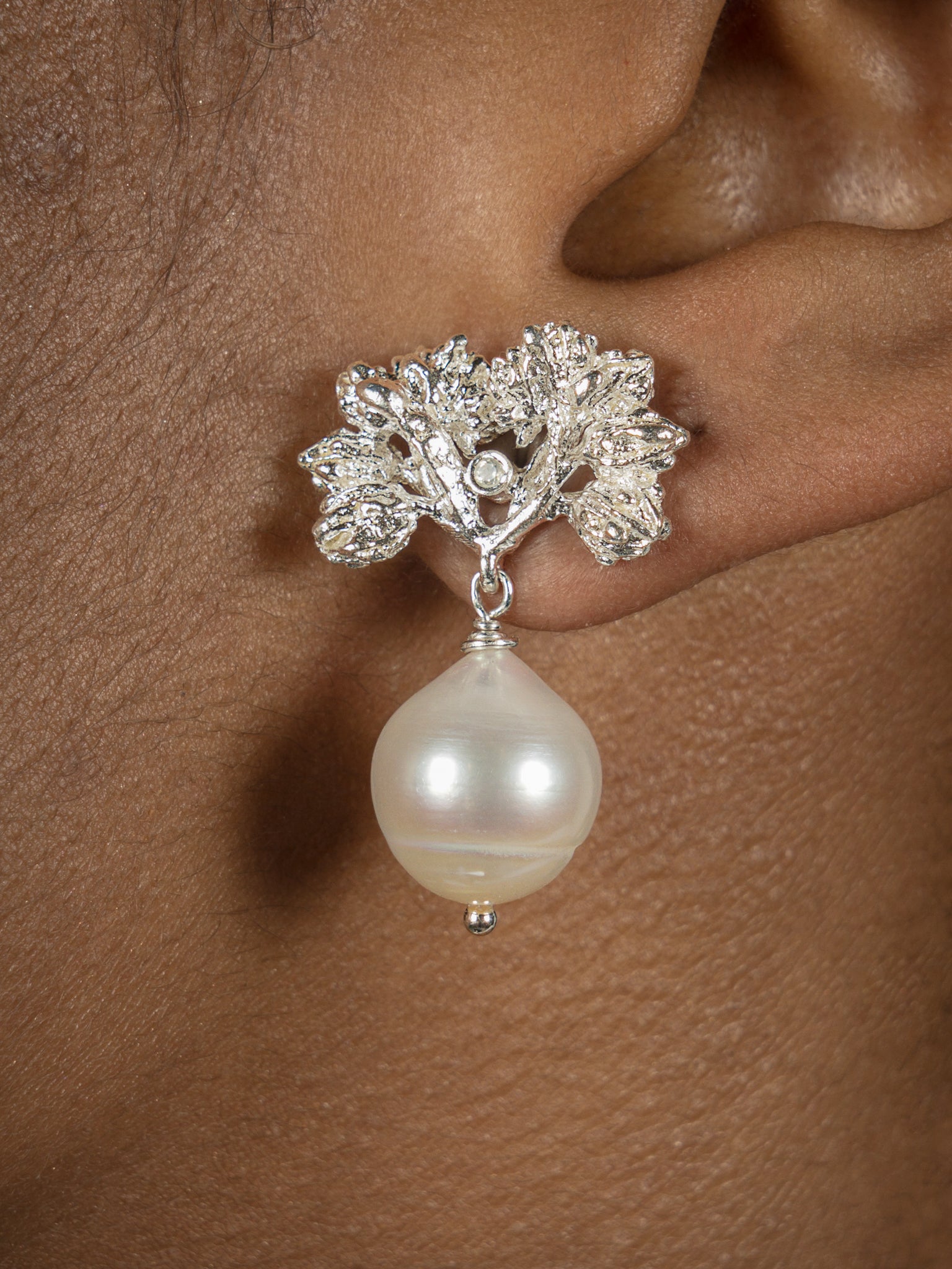 A woman's ear with a Cremilde Bispo Jewellery Pearly Forest Earrings.