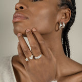 A black woman exuding maximum style while wearing Cremilde Bispo Jewellery's Essential Leaf Hoops and a set of silver rings.