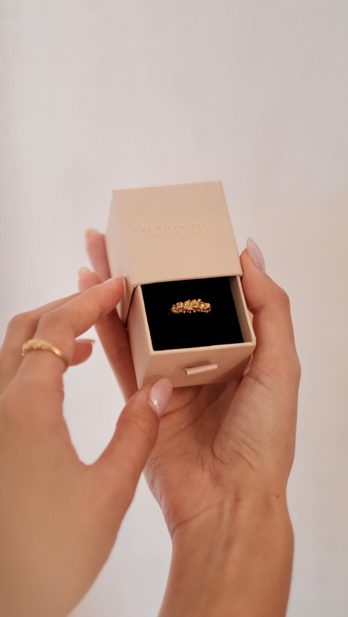 A woman holding The Blooms Ring in Gold plated sterling silver, by Cremilde Bispo Jewellery in the brand's gift jewellery box.
