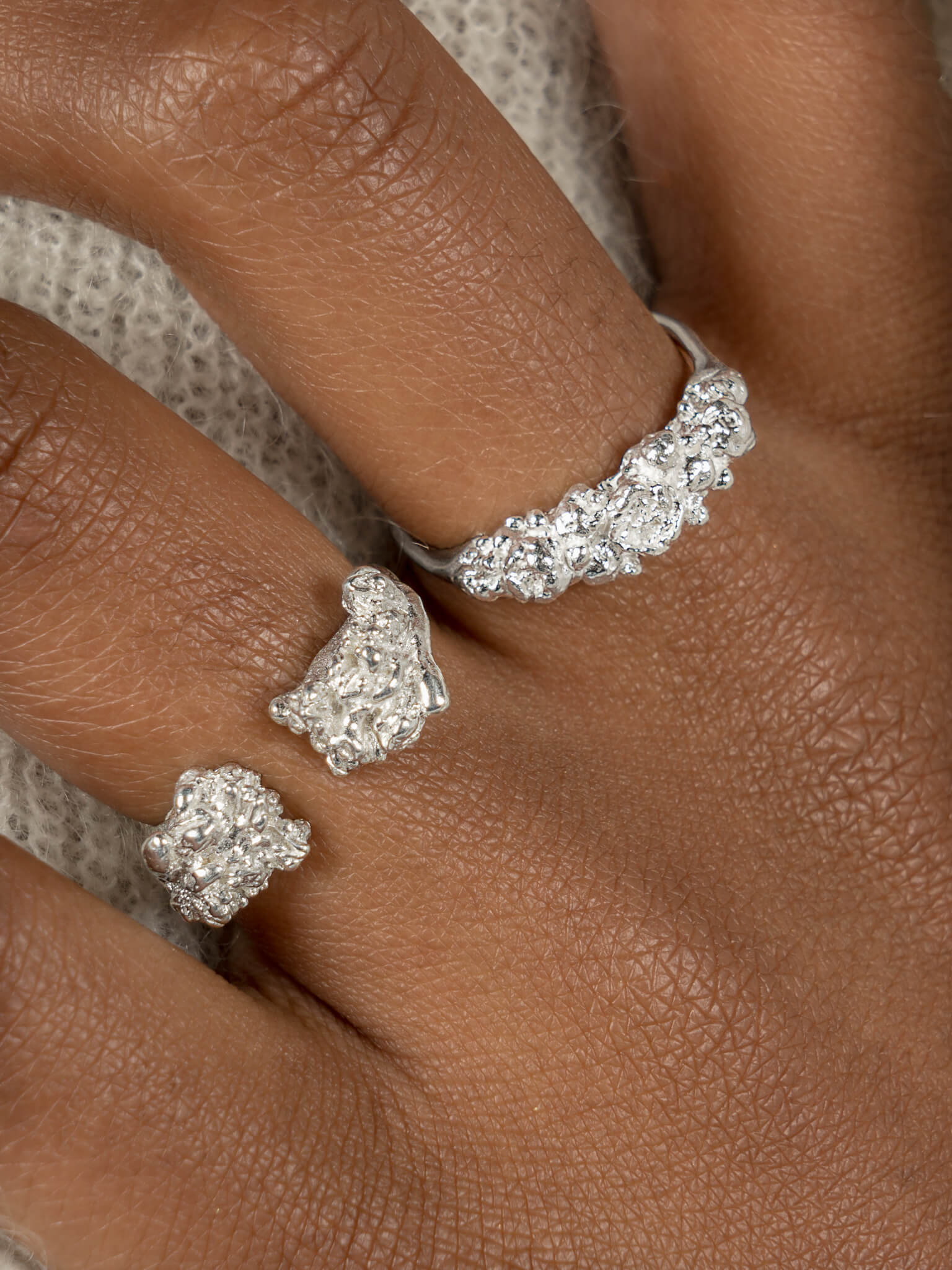 A close-up of a woman’s hand, featuring 2 rings, one of them is the Cremilde Bispo Jewellery Blooms Ring, in sterling silver, adorned with a beautiful cluster of organic, nature inspired embellishments.