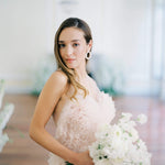 A refined bride in a pink dress holding a bouquet of white flowers, radiating nature's beauty with the Cremilde Bispo Jewellery's Garden's Delight earrings, in sterling silver.