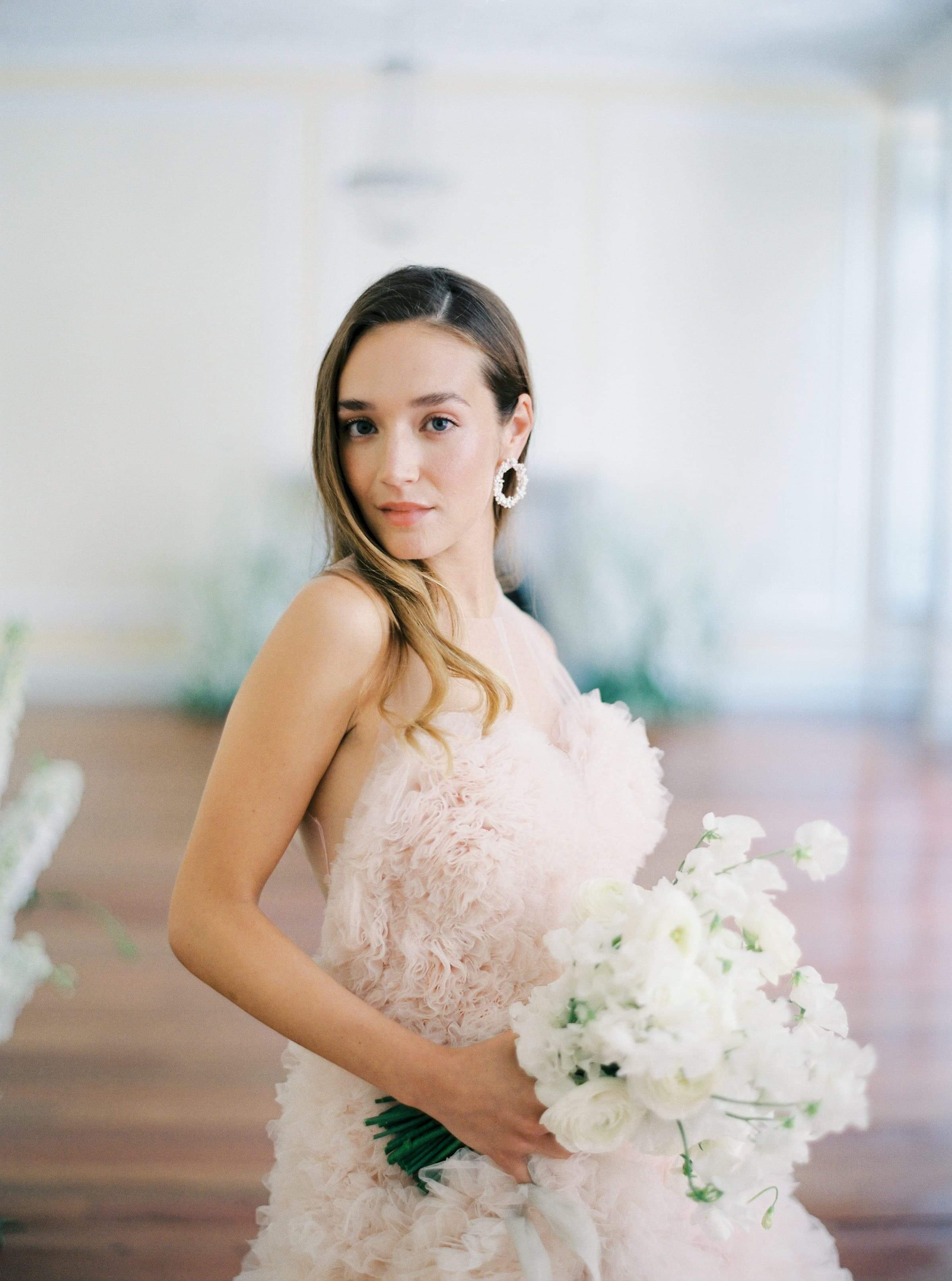 A refined bride in a pink dress holding a bouquet of white flowers, radiating nature's beauty with the Cremilde Bispo Jewellery's Garden's Delight earrings, in sterling silver.