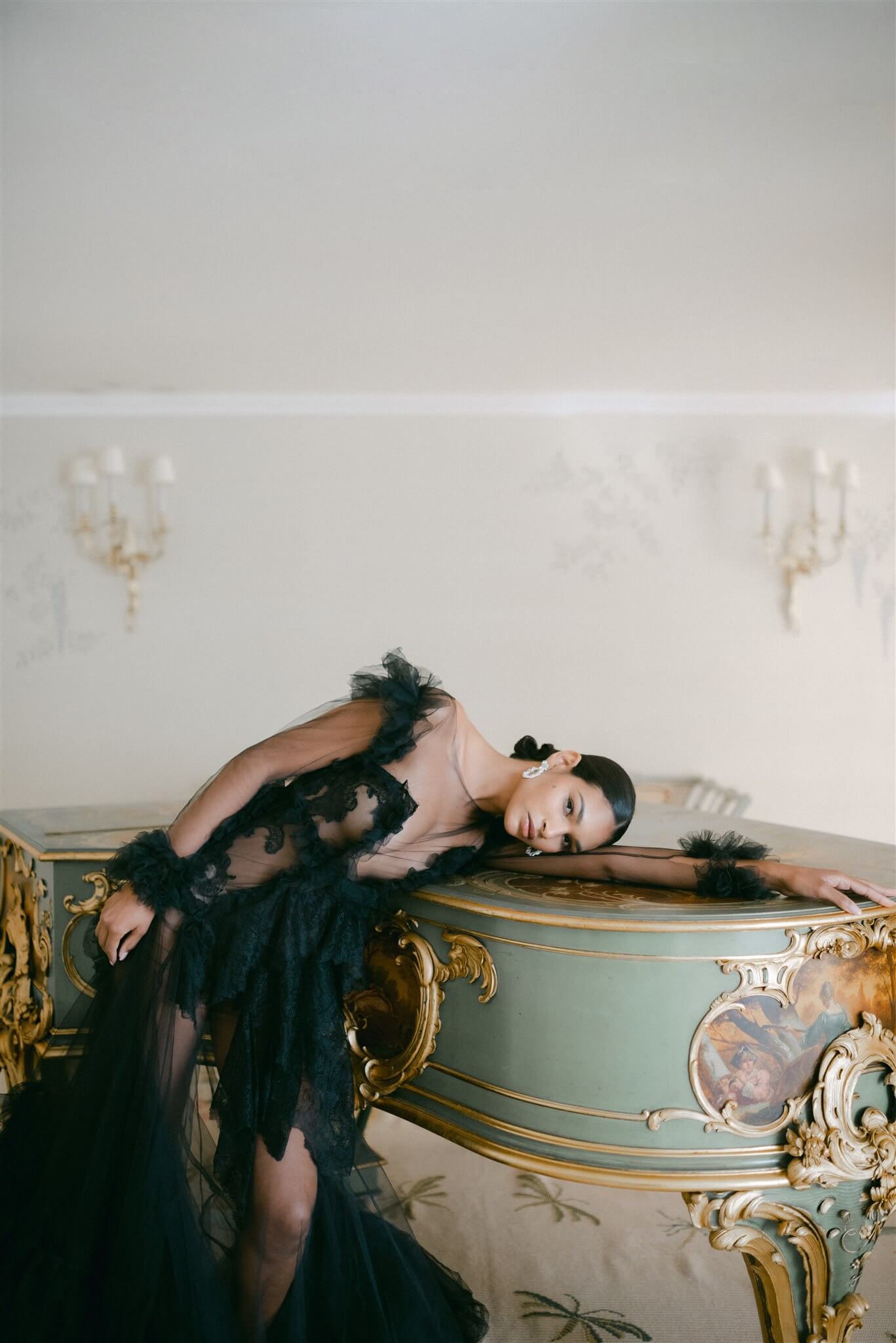 A sophisticated woman in a lavish black gown leaning on a grand piano wearing the Cremilde Bispo Jewellery Garden's Delight statement earrings in sterling silver.