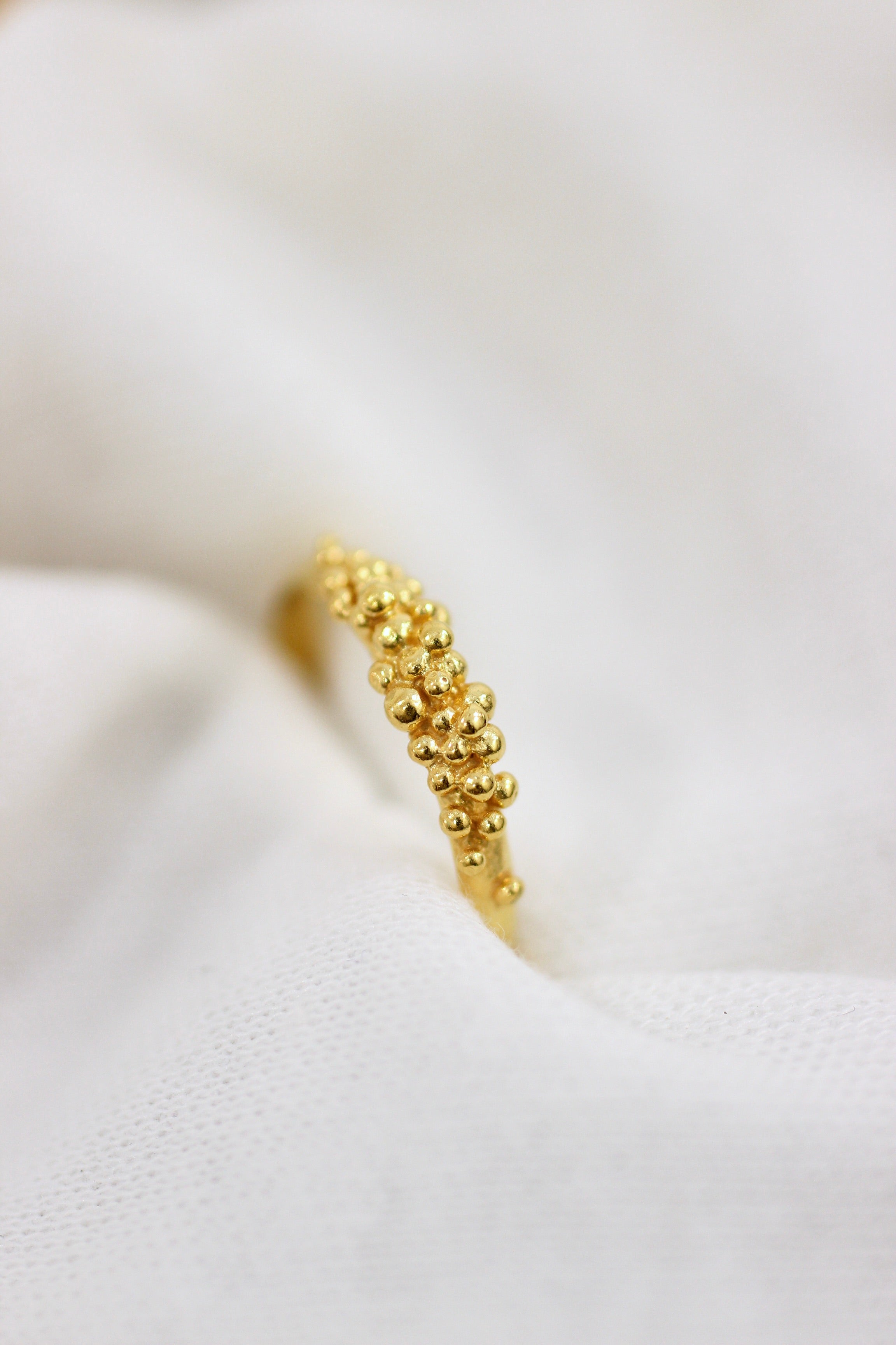 An exquisite Cremilde Bispo Jewellery 18K Yellow Gold Essential Dot Ring displayed elegantly on a white cloth, adding to the allure of your jewellery collection.