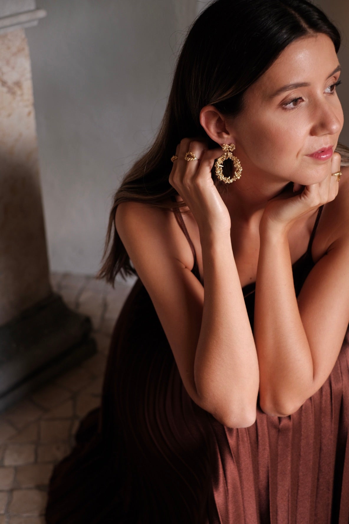 A woman in a brown dress is posing for a photo, showcasing her opulence with the stunning Cremilde Bispo Jewellery's Garden's Delight II GP earring set.