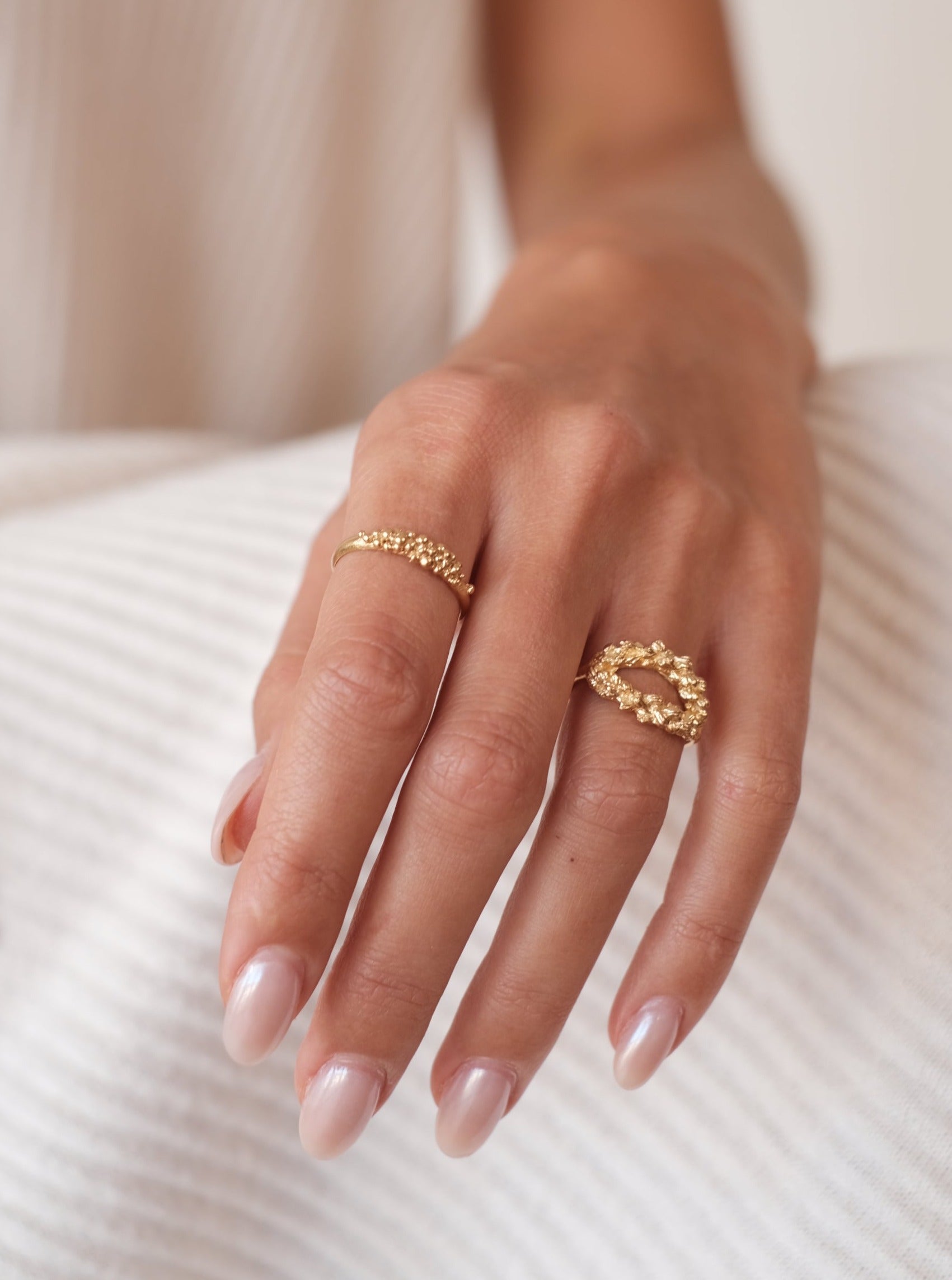 A woman's hand adorned with the Cremilde Bispo Jewellery Essential Dot Ring GP exudes timeless elegance and luxurious sophistication.