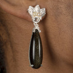 An elegant woman wearing a pair of The Muse III Obsidian earrings by Cremilde Bispo Jewellery, showcasing exquisite jewelry.