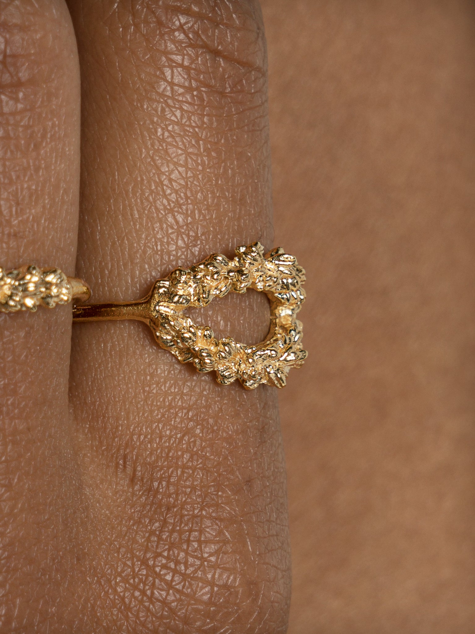 A woman's hand adorned with a Cremilde Bispo Jewellery Laurel Ring GP, showcasing Ancient Rome's grandeur and featuring exquisite hand-carved floral foliage.