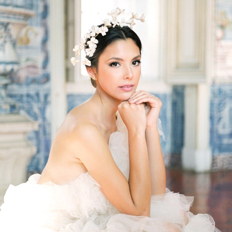 A luxurious woman in a white dress sitting on the floor, wearing The Muse I necklace by Cremilde Bispo Jewellery.