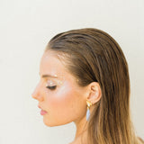 A woman in a white dress is wearing a pair of earrings adorned with The Muse III Chalcedony from Cremilde Bispo Jewellery.