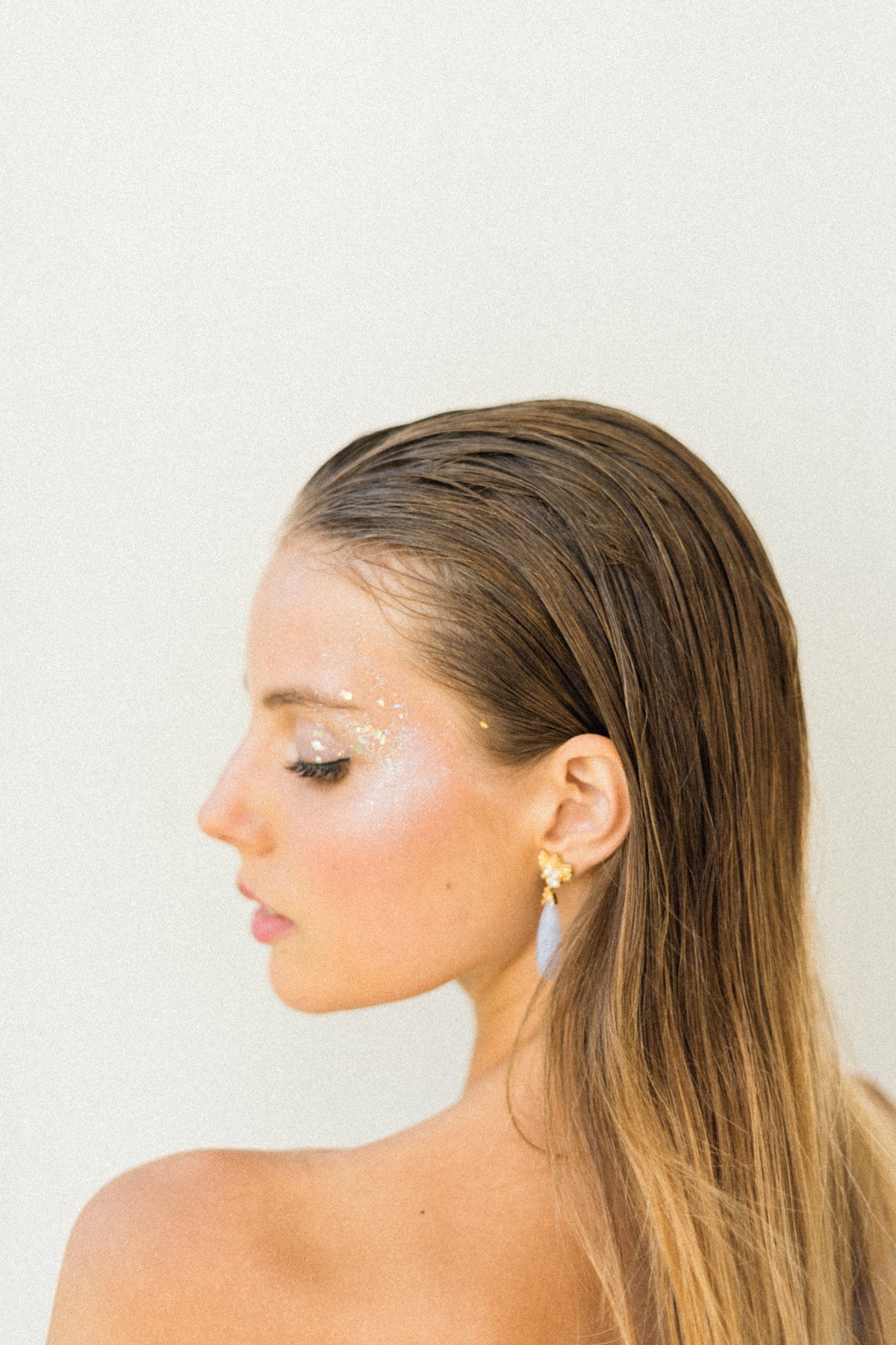 A woman in a white dress is wearing a pair of earrings adorned with The Muse III Chalcedony from Cremilde Bispo Jewellery.