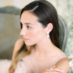 A Muse II of elegance in a luxurious pink dress, gracefully sitting on a chair by Cremilde Bispo Jewellery.