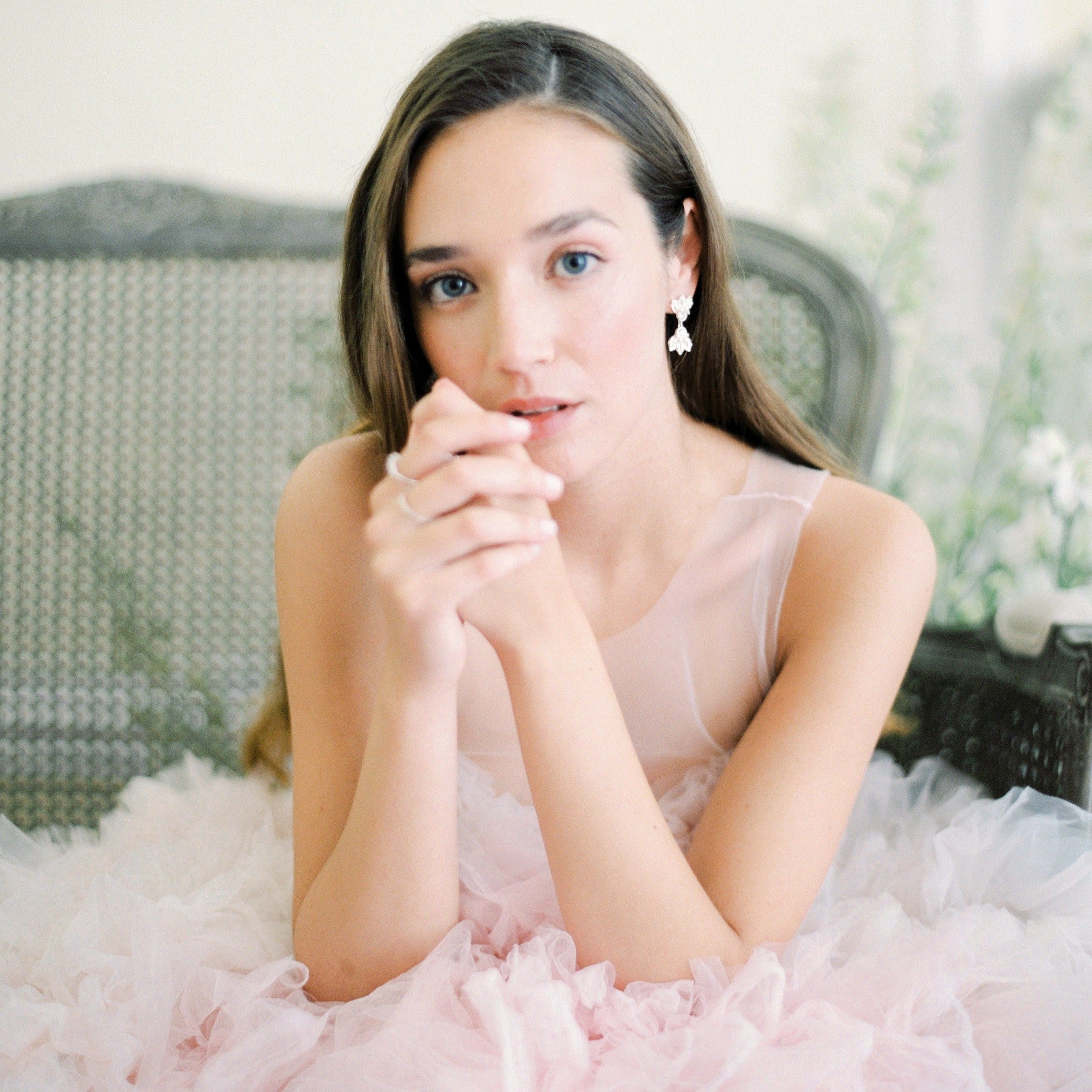 An elegant girl in a pink dress, exuding luxury, sitting on a couch with The Muse II by Cremilde Bispo Jewellery.