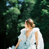 A vintage-inspired bride in a blue tulle dress sitting on a railing, adorned with elegant Cremilde Bispo Jewellery's Guipure GP lace artistry.