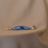 These silver Cremilde Bispo Jewellery Muse III Kyanite earrings feature blue stones on a beige background, making them the perfect jewelry accessory.