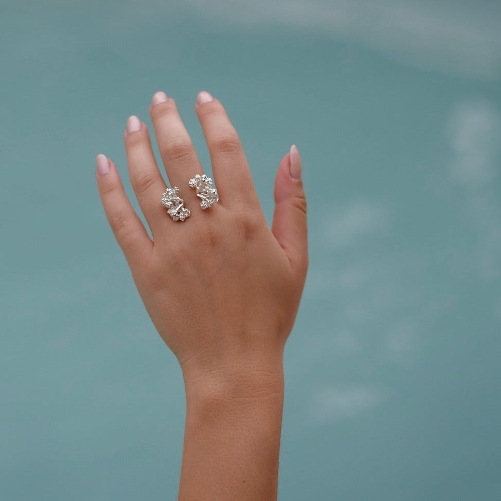 A close-up of a woman's hand wearing the handcrafted Garden Ring in sterling silver, embedded with Quartz gemstones, from Cremilde Bispo Jewellery.