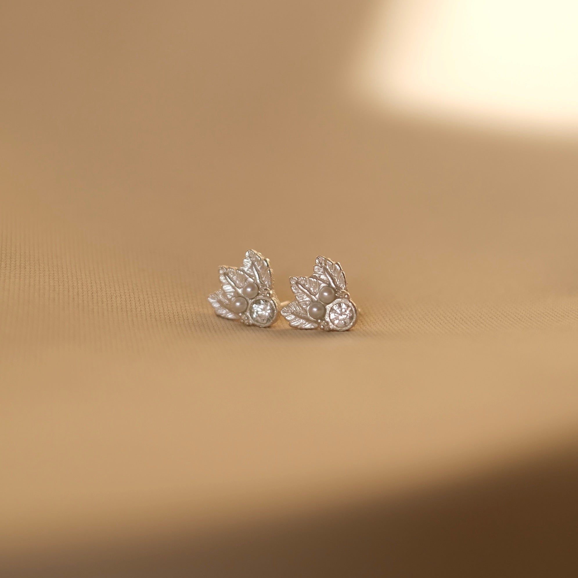 A pair of luxurious Cremilde Bispo Jewellery Muse I silver stud earrings on a table.