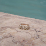 A handcrafted gold ring from Lisbon Atelier elegantly adorns the surface of a marble pool, exuding the splendor of the Cremilde Bispo Jewellery Valley ring.