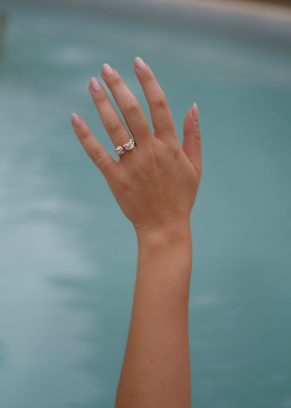 A woman's hand in Lisbon Atelier pool with a Cremilde Bispo Jewellery Valley ring on it.