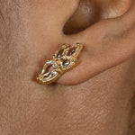 A woman's ear adorned with a pair of Essential Drops Earrings from the Cremilde Bispo Jewellery, featuring pear-like Quartz gemstones..