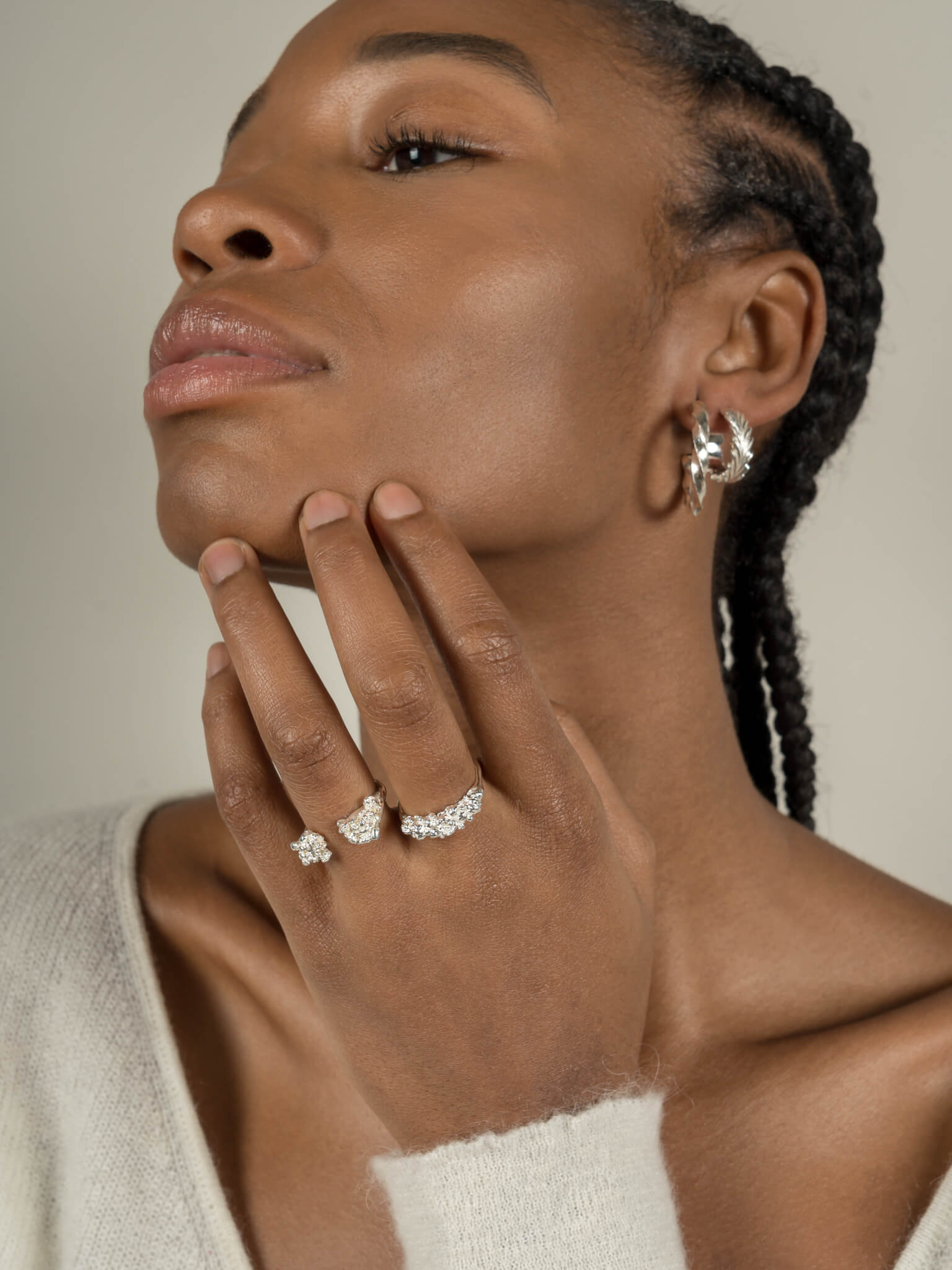 A black woman exuding maximum style while wearing Cremilde Bispo Jewellery's Essential Leaf Hoops and a set of silver rings.