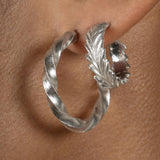 A close up of a fashionable woman's ear with a pair of Cremilde Bispo Jewellery Essential Twisted Hoops, in Sterling silver.