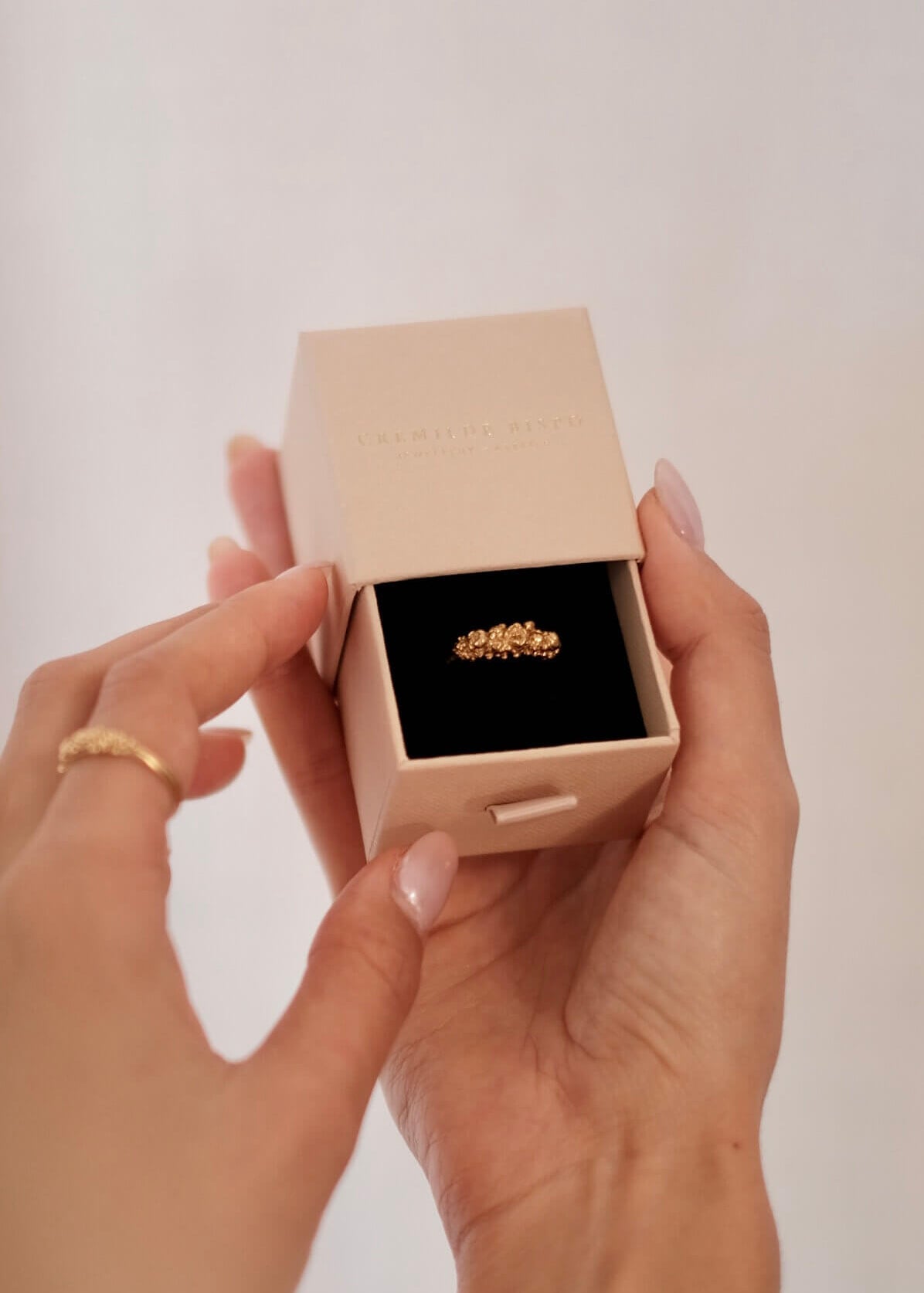 A woman holding The Blooms Ring in Gold plated sterling silver, by Cremilde Bispo Jewellery in the brand's gift jewellery box.