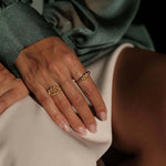 A woman wearing The Blooms Ring GP by Cremilde Bispo Jewellery, in Gold plated sterling silver, and a silk deep green blouse, exuding a luxury vibe.