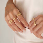 A woman wearing The Blooms Ring GP by Cremilde Bispo Jewellery, in Gold plated sterling silver, and a silky white dress, exuding a luxury vibe.