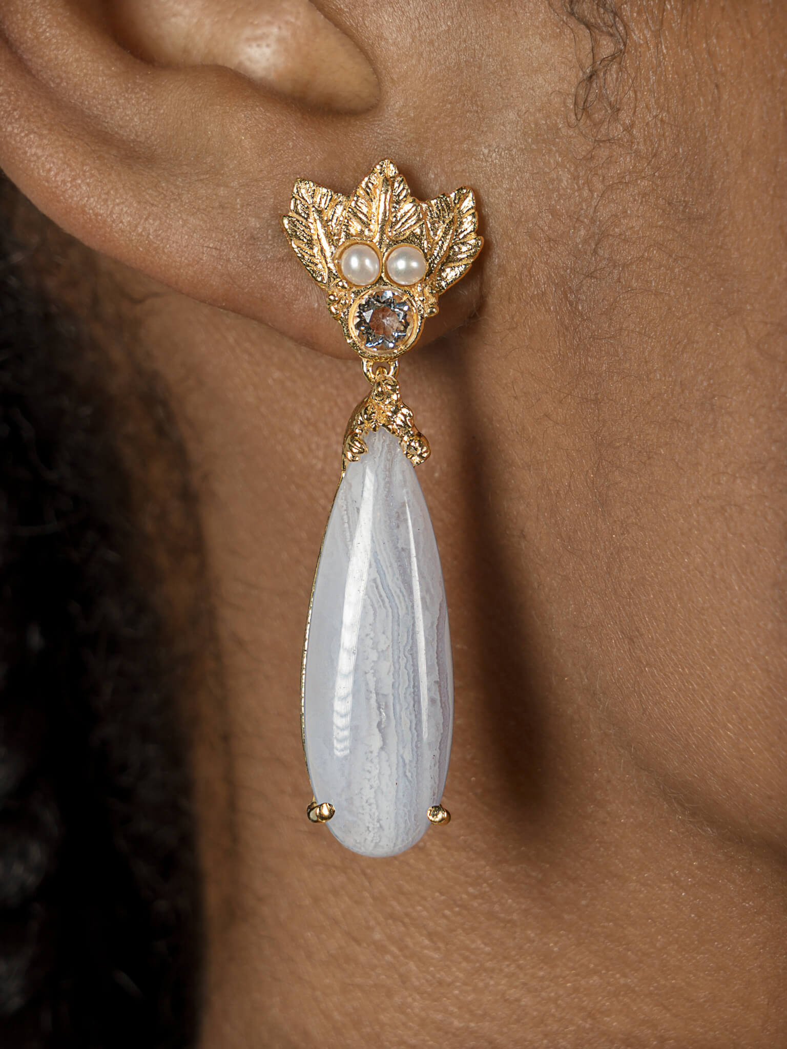A woman's ear with The Muse III Chalcedony earring adorned with cultured fresh-water pearls from Cremilde Bispo Jewellery.