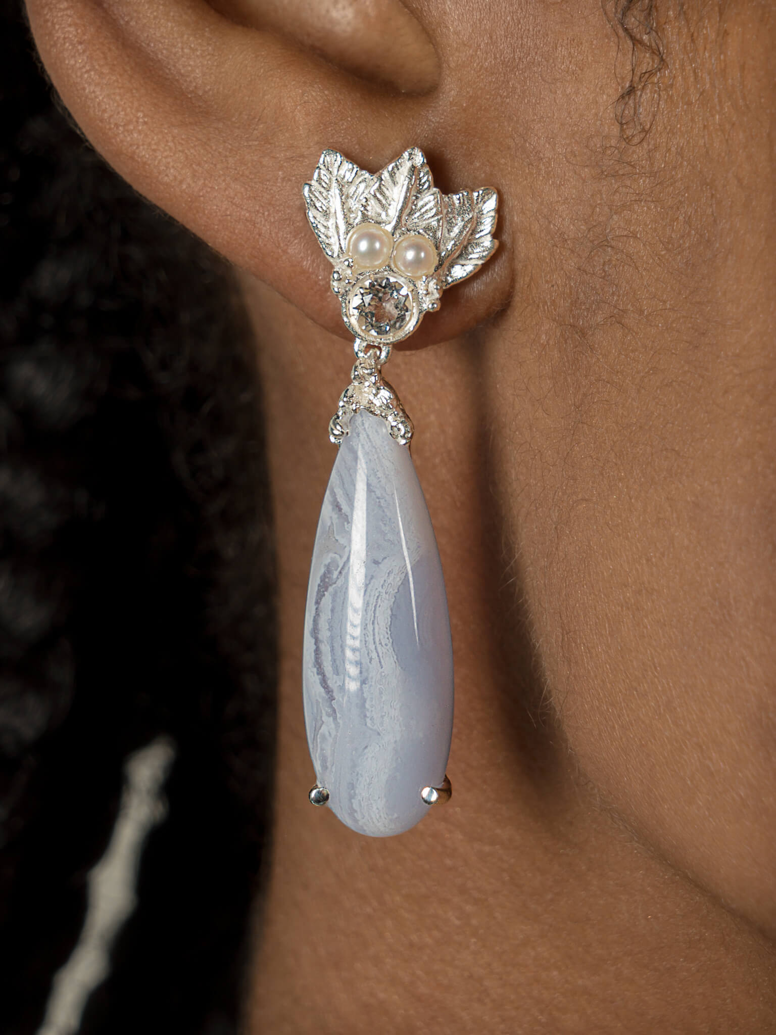 A woman wearing a pair of Muse III Chalcedony earrings, made of .925 silver by Cremilde Bispo Jewellery.