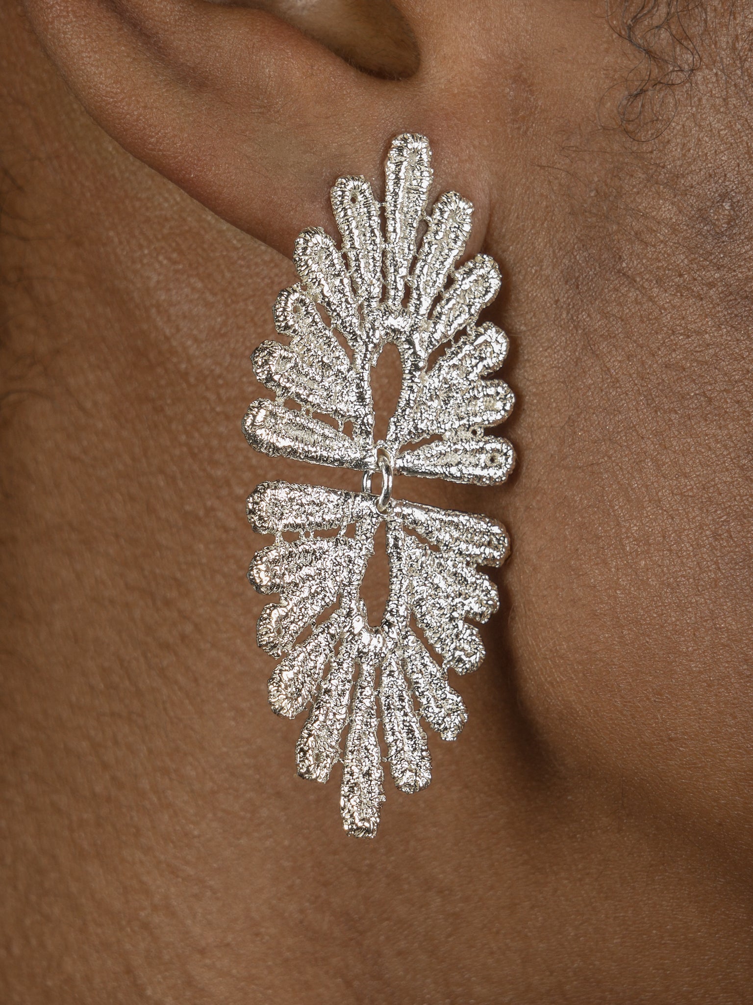 A close up of a woman's ear adorned with a pair of vintage-inspired silver Cremilde Bispo Jewellery Guipure Earrings, showcasing delicate lace artistry.