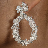 A woman's ear adorned with the Cremilde Bispo Jewellery Garden's Delight statement earrings. Handcrafted from sterling silver, these earrings feature meticulously hand-sculpted floral accents and an elegant drop-shaped design that gently sways with grace.