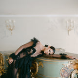 A sophisticated woman in a lavish black gown leaning on a grand piano wearing the Cremilde Bispo Jewellery Garden's Delight statement earrings in sterling silver.