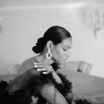 A sophisticated woman in a lavish black gown leaning on a grand piano wearing the Cremilde Bispo Jewellery Garden's Delight statement earrings in sterling silver.