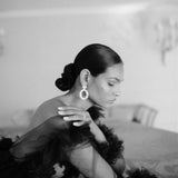 A sophisticated woman in a lavish black gown leaning on a grand piano wearing the Cremilde Bispo Jewellery Garden's Delight statement earrings in sterling silver.