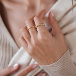 A woman showcasing an elegant 18K Yellow Gold Essential Dot Ring from the Cremilde Bispo Jewellery collection.