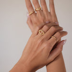 A woman's hand showcasing her jewellery collection with two elegant rings, including the exquisite Cremilde Bispo Jewellery 18K Yellow Gold Essential Dot Ring.