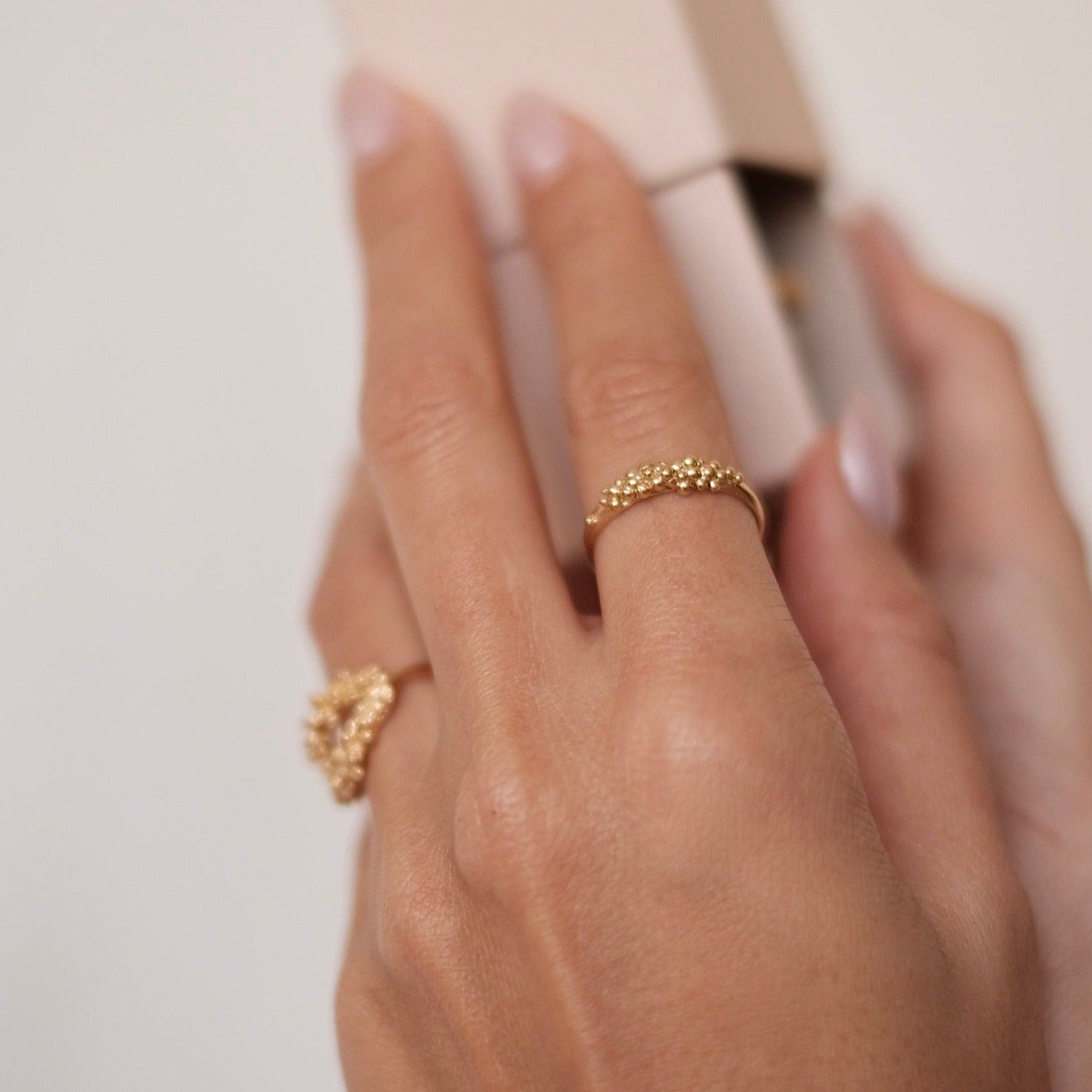 A woman's hand showcasing an exquisite Cremilde Bispo Jewellery Essential Dot Ring crafted with 18K Yellow Gold.