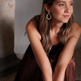A woman in a brown dress sitting on the floor, surrounded by Cremilde Bispo Jewellery's Garden's Delight II GP opulence.
