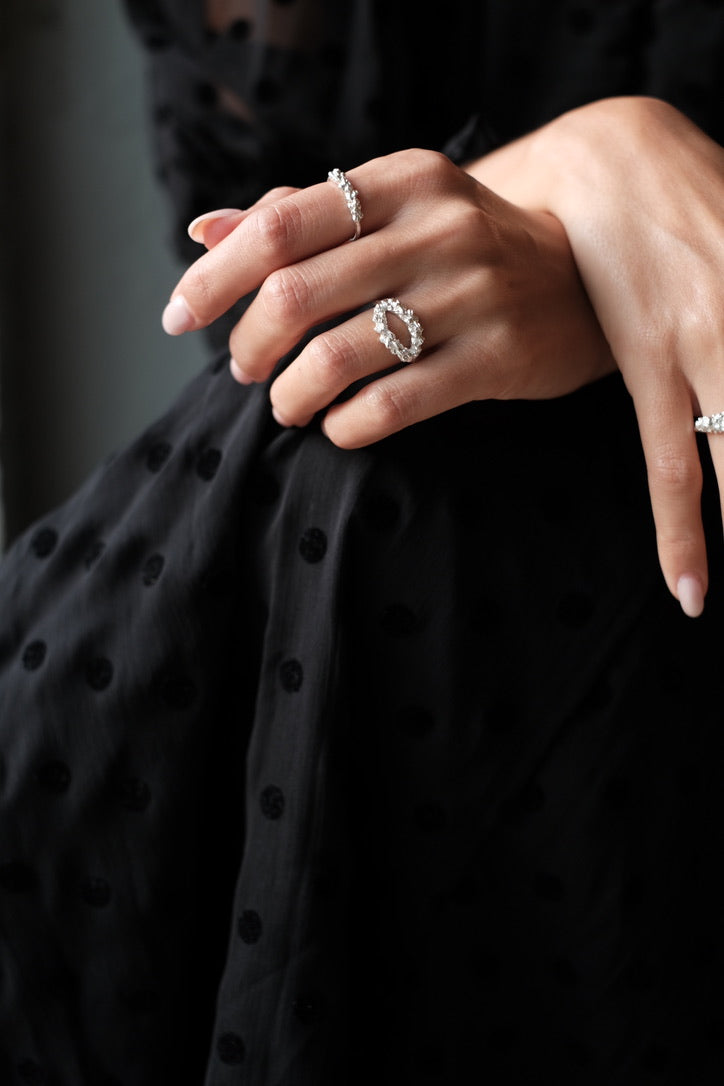 A woman wearing a polka dot dress adorned with a dazzling Cremilde Bispo Jewellery Laurel Ring, embracing the timeless beauty of nature.