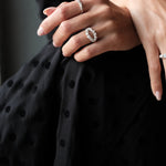 A woman wearing a polka dot dress adorned with a dazzling Cremilde Bispo Jewellery Laurel Ring, embracing the timeless beauty of nature.