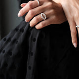 A woman wearing a polka dot dress adorned with a dazzling Cremilde Bispo Jewellery Laurel Ring, embracing the timeless beauty of nature.