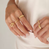 A woman adorned in an elegant white dress, complimented by exquisite Cremilde Bispo Jewellery's Laurel Ring GP inspired by Ancient Rome's grandeur. Each ring features meticulously hand-carved floral foliage designs reminiscent of the opulence.